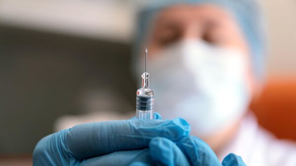 Медик готовит шприц с вакциной