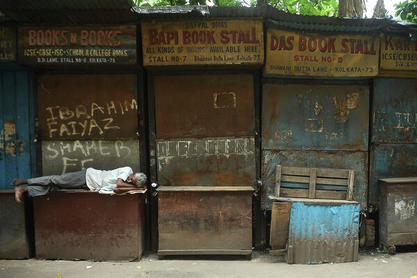 Мужчина спит в закрытом рынке в Калькутте, Индия