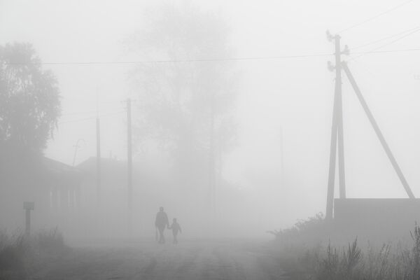 Прохожие в утреннем тумане в селе Вьюны Новосибирской области