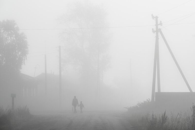 Прохожие в утреннем тумане в селе Вьюны Новосибирской области