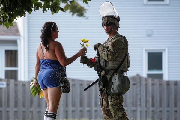 Женщина вручает цветы члену Национальной гвардии США в штате Висконсин
