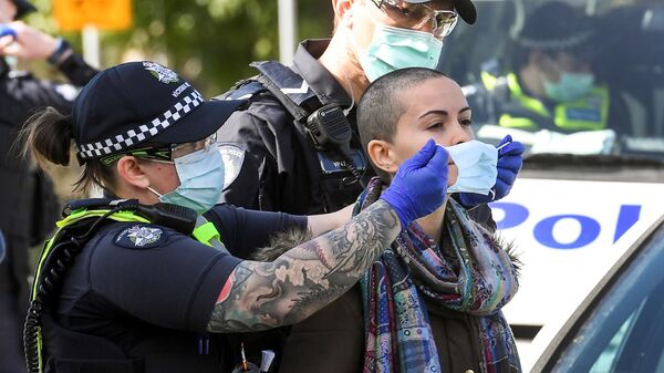 Полицейский надевает маску на задержанного во время демонстрации против карантинных мер, связанных с коронавирусом в Мельбурне, Австралия