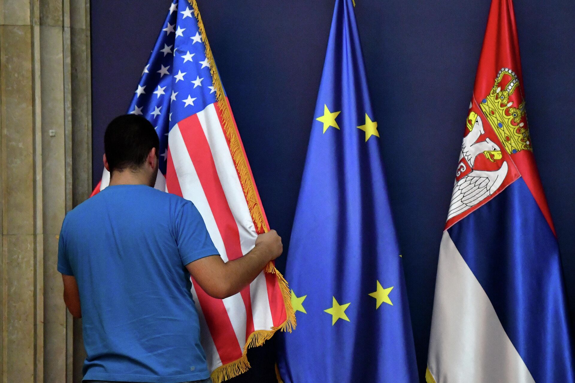 Мужчина расставляет флаг США рядом с флагом Европейского Союза и Сербии - РИА Новости, 1920, 07.09.2020