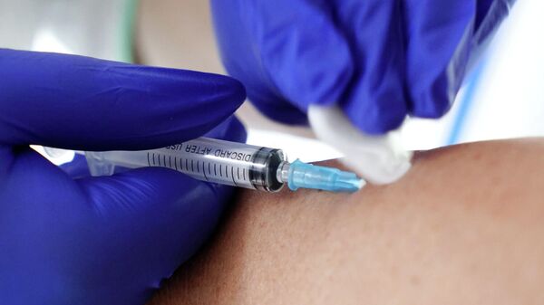 Медик делает прививку с вакциной против гриппа