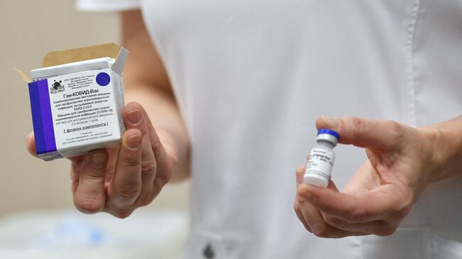 Медицинский работник демонстрирует вакцину против COVID-19 во время вакцинации добровольцев в Москве