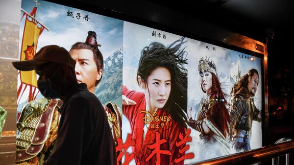 Мужчина проходит мимо плаката фильма Мулан студии Disney на автобусной остановке в Пекине