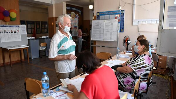 Мужчина и члены избирательной комиссии на избирательном участке, где проходят выборы губернатора Севастополя