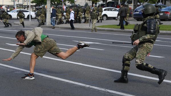 Сотрудник правоохранительных органов задерживает участника несанкционированной акции протеста в Минске