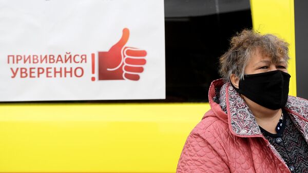 Жительница Казани у машины скорой помощи, где проходит бесплатная вакцинация от гриппа