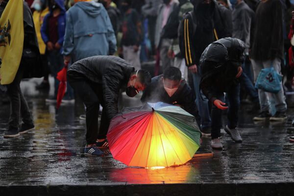 Демонстранты держат факелы под зонтиком во время акции протеста против экономической политики правительства, роста безработицы в Кито, Эквадор