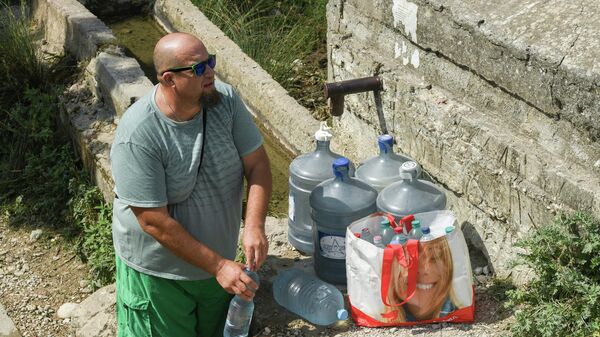 Мужчина набирает воду из родника в селе Дружное Симферопольского района