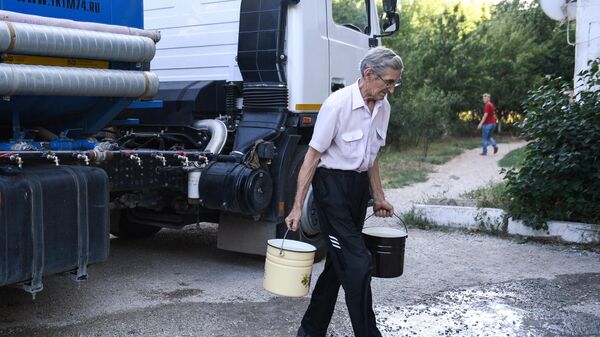 Житель Cимферополя набирает в емкости питьевую воду, привезенную в цистернах