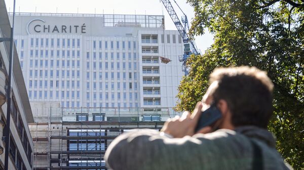 Мужчина звонит по телефону на фоне клиники Шарите в Берлине