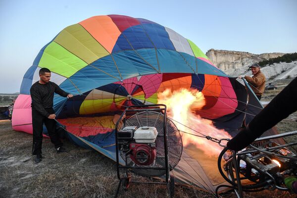 Участники фестиваля воздухоплавания готовят воздушный шар к полету у подножия Белой скалы в Белогорском районе республики Крым