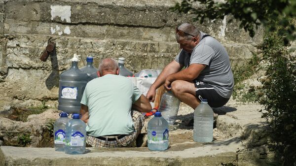 Мужчины набирают воду из родника в селе Дружное Симферопольского района