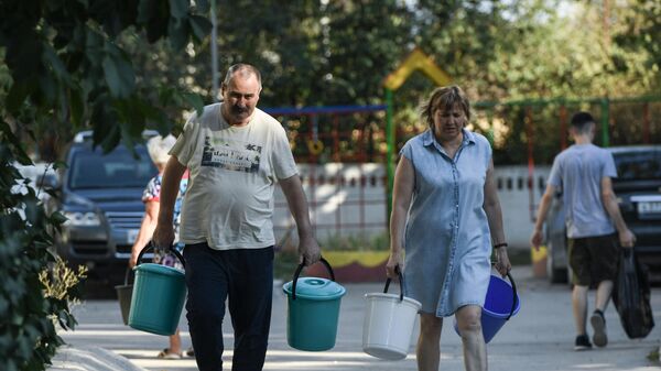 Жители Cимферополя идут чтобы набрать в емкости питьевую воду, привезенную в цистернах
