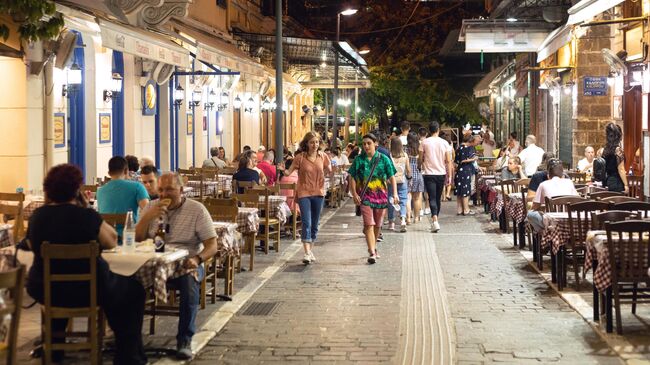 Посетители за столиками летнего кафе в Афинах