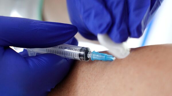 Медик делает прививку с вакциной 