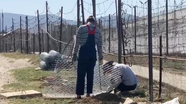 Рабочие заделывают лаз на контрольно-следовой полосе в исправительной колонии № 2 в Дагестане
