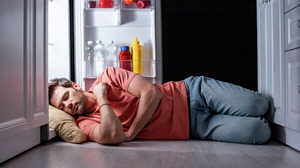 Мужчина спит возле холодильника
