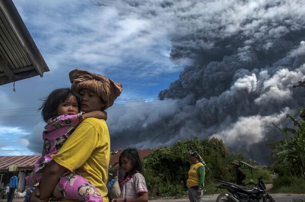 Местные жители в деревне у подножия действующего вулкана Синабунг в провинции Северная Суматра в Индонезии