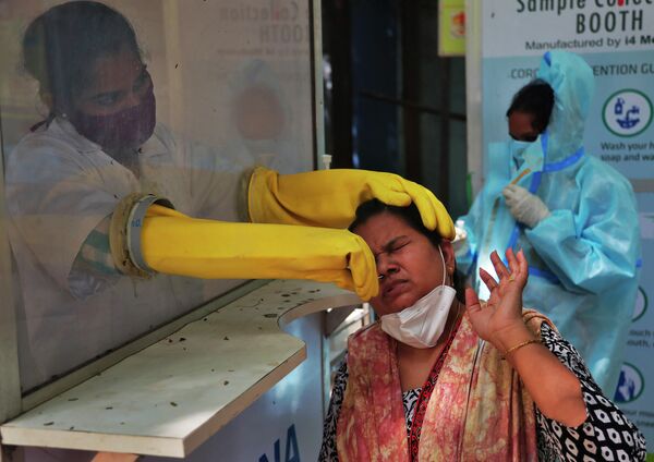 Медицинский работник берет мазок из носа для тестирования на COVID-19 в Хайдарабаде, Индия