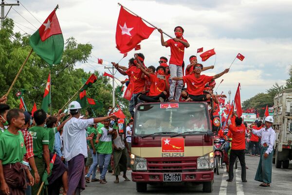 Сторонники партии Национальная Лига за демократию в кортеже проезжают мимо сторонников оппозиционной партии Союз солидарности и развития во время предвыборной кампании в Вундвине, недалеко от Мандалая, Мьянма