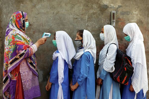 Проверка температуры у учеников перед входом в класс в Пешаваре, Пакистан