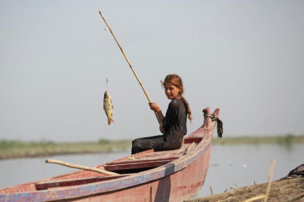 Девушка ловит рыбу в болотах Южного округа Чибаиш провинции Ди-Кар, Ирак