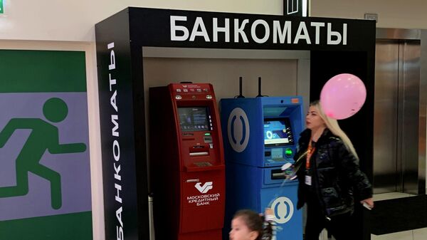 Женщина с ребенком проходят мимо банкоматов