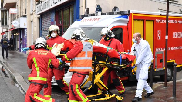 Французские пожарные несут раненого возле бывшего офиса французского сатирического журнала Charlie Hebdo в Париже
