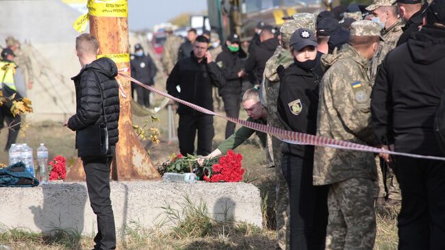 Люди несут цветы на место крушения самолета Ан-26 под Харьковом