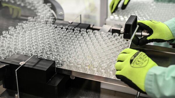Лаборанты обрабатывают флаконы для новой вакцины от коронавируса AstraZeneca