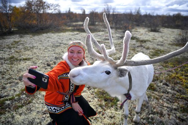Девушка фотографируется с северным оленем на территории Центра арктического туризма в Ненецком автономном округе