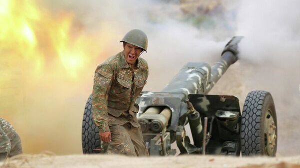 Военнослужащий стреляет из артиллерийского орудия во время боя с азербайджанскими силами в Нагорном Карабахе