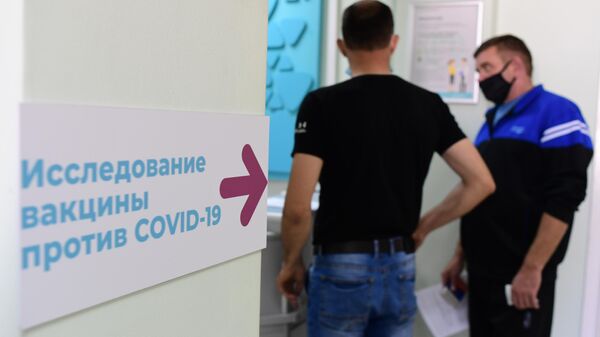 Мужчины стоят в очередь на вакцину возле процедурного кабинета поликлиники Москвы