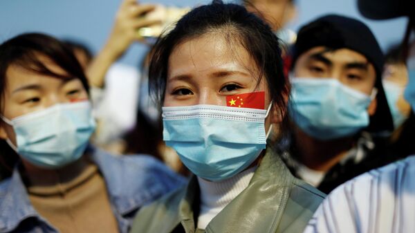 Люди в защитных масках на церемонии поднятия государственного флага на площади Тяньаньмэнь по случаю 71-й годовщины образования КНР