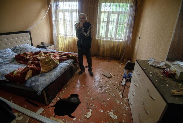 Мужчина показывает дом, поврежденный в результате обстрела по общине Иванян Нагорного Карабаха