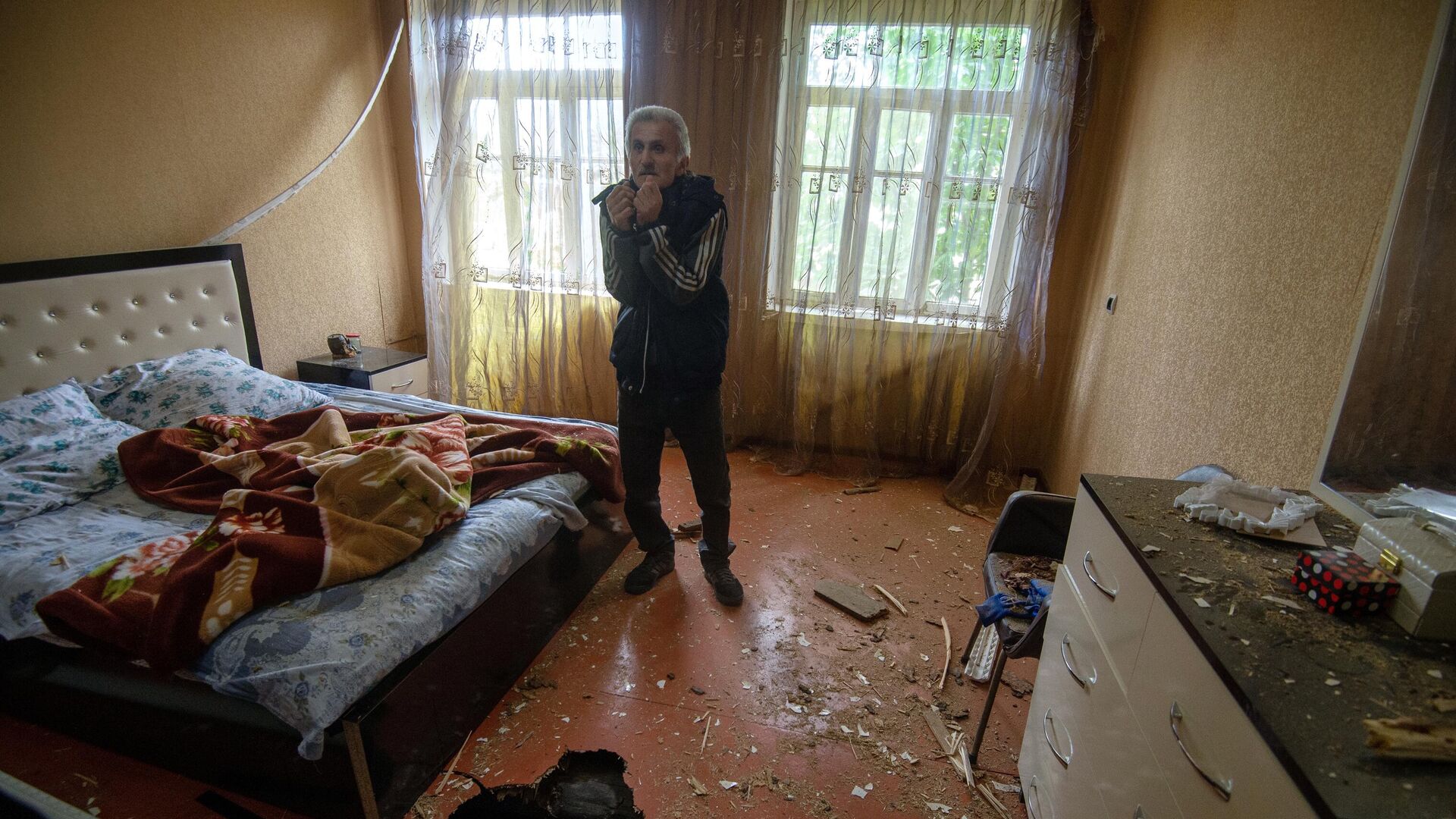 Мужчина показывает дом, поврежденный в результате обстрела по общине Иванян Нагорного Карабаха - РИА Новости, 1920, 01.10.2020