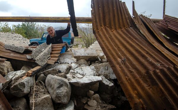 Мужчина у хозяйственной постройки, разрушенной в результате обстрела общины Иванян Нагорного Карабаха