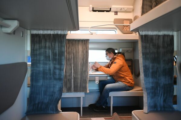Мужчина в павильоне с макетом нового плацкартного вагона для поездов дальнего следования