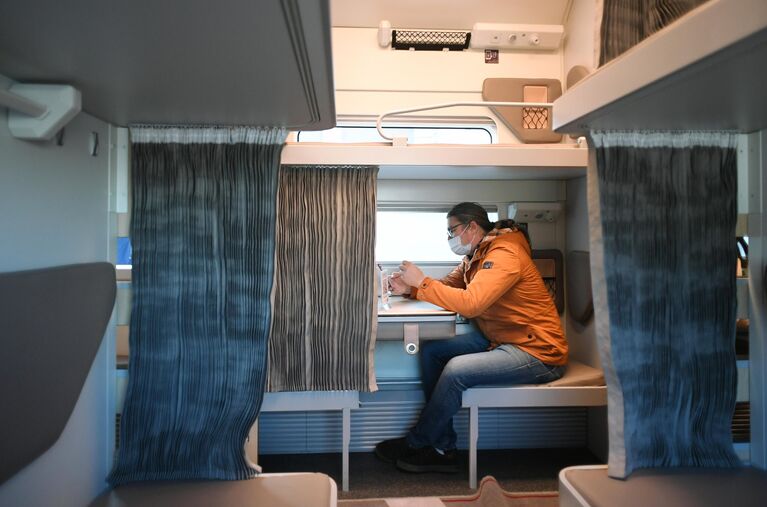 Мужчина в павильоне с макетом нового плацкартного вагона для поездов дальнего следования Мужчина в павильоне с макетом нового плацкартного вагона для поездов дальнего следования