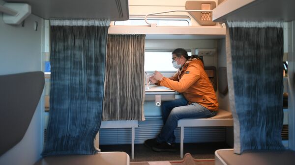Мужчина в павильоне с макетом нового плацкартного вагона для поездов дальнего следования