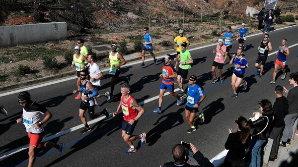 Athletes run past burned out area near the village of Mati during the  36th Athens Classic Marathon 'The authentic' from the town of Marathon to the Panathenaic stadium in Athens on November 11, 2018. (Photo by Louisa GOULIAMAKI / AFP)
