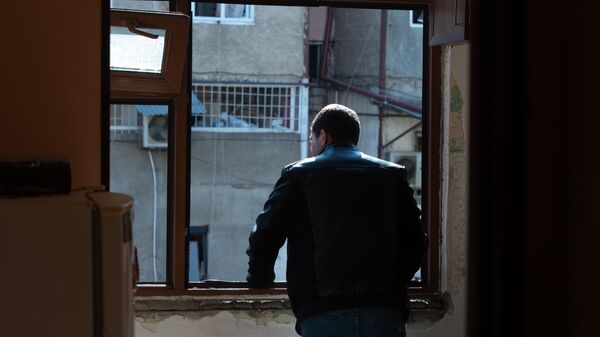 Мужчина в окне с выбитыми стеклами в одной из квартир жилого дома, пострадавшего в результате обстрела Степанакерта в Нагорном Карабахе