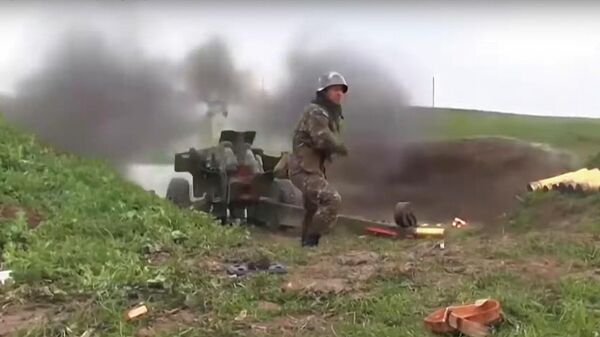 Военнослужащий стреляет из пушки по позициям вооруженных сил Азербайджана на линии соприкосновения в Нагорном Карабахе. Стоп-кадр видео