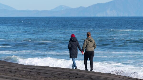 Молодые люди гуляют на Халактырском пляже Тихоокеанского побережья полуострова Камчатка