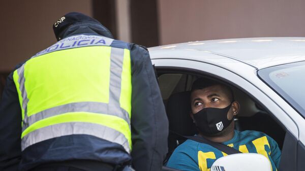 Сотрудник полиции общается с водителем автомобиля на контрольно-пропускном пункте при въезде в Мадрид