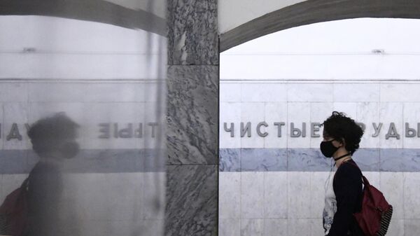 Девушка в маске в вестибюле станции метро Чистые пруды в Москве