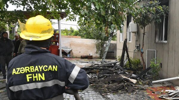 Сотрудник пожарной службы возле дома, пострадавшего в результате обстрела города Барда